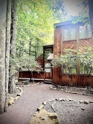 Escape to a secluded cabin surrounded by trees, with a wooden staircase leading to a cozy entrance.