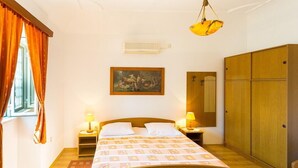 Une chambre à coucher comprenant un lit, deux lampes de chevet, un tableau au mur, une armoire et un appareil de climatisation.