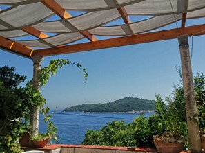 A covered outdoor area with a view of the sea and a distant island.
