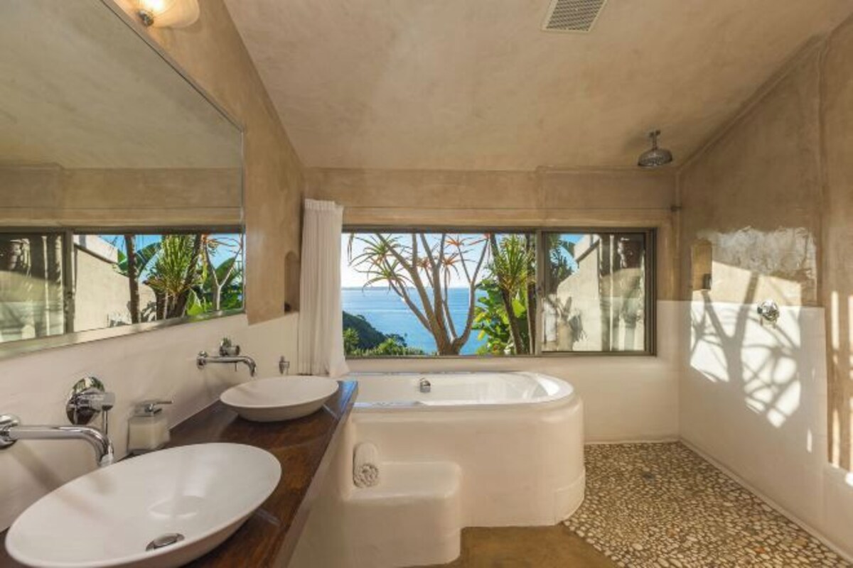 Un baño moderno con una bañera amplia, dos lavamanos y un espejo grande.