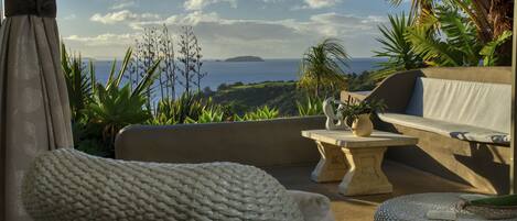 A cozy outdoor seating area with a view of the ocean and a distant island.