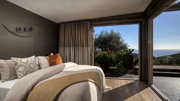 A bedroom with a large bed, a view of the outdoors, and a modern design.