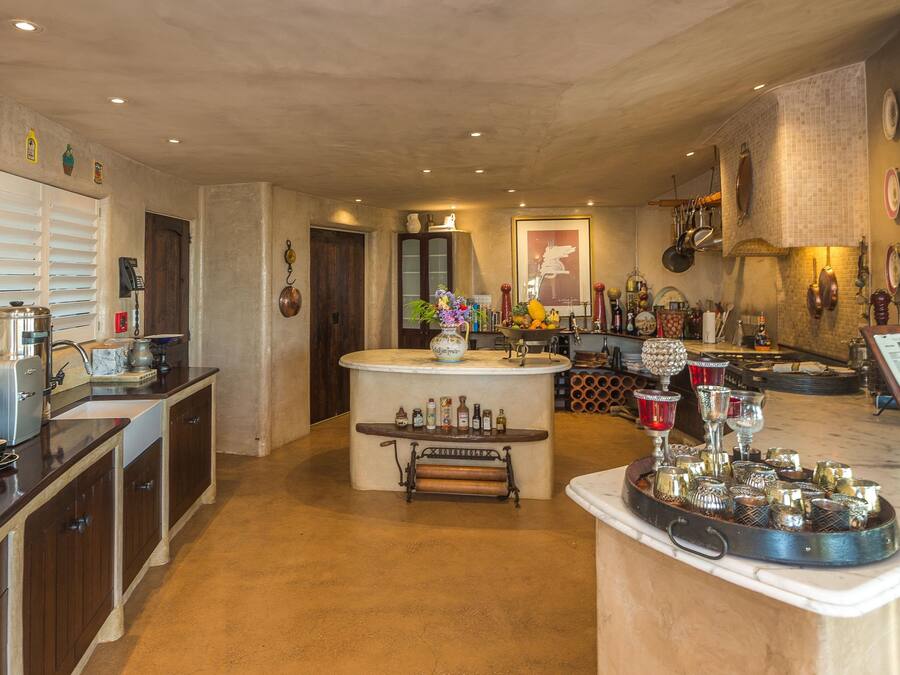 A spacious kitchen with a central island, wooden cabinets, and a variety of kitchenware and appliances.