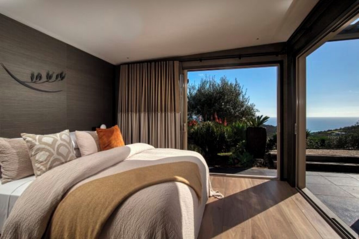 Un dormitorio moderno con una cama grande, vistas al exterior y un elemento decorativo en la pared.