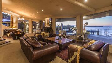 A spacious living room with leather sofas, a wooden coffee table, and a view of the sea.