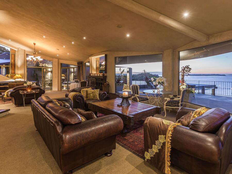 A spacious living room with leather sofas, a wooden coffee table, and a view of the sea.