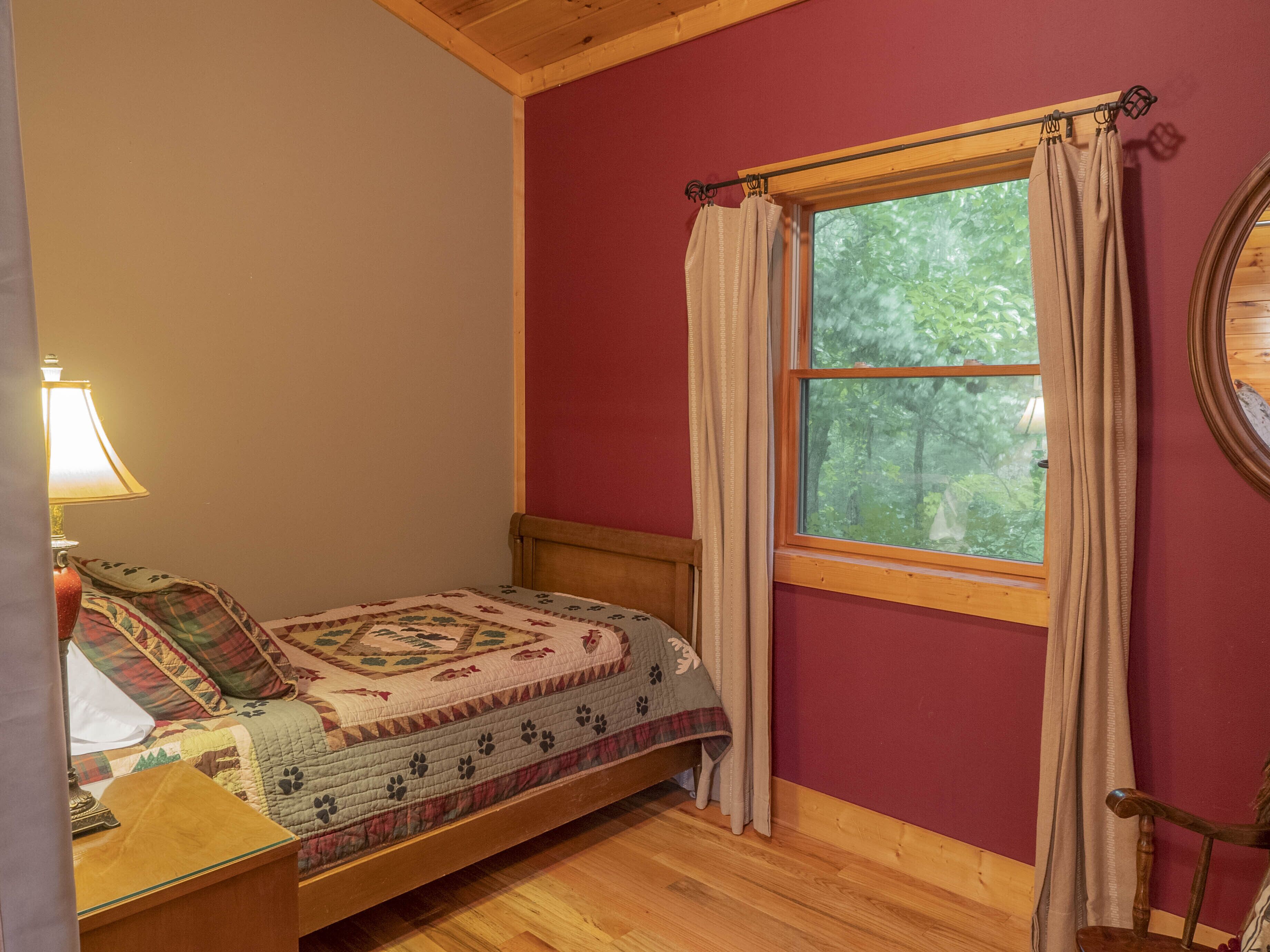 Un dormitorio acogedor con una cama de madera, una ventana con cortinas y una lámpara.
