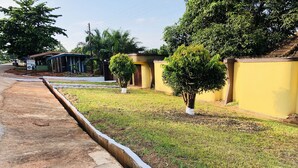 A residential area with a paved sidewalk, a drainage ditch, and a small tree. - 🌟🧡FREE AIRPORT/BUS TERMINAL TRANSPORTATION (Kumasi)