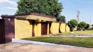 A building with a yellow facade, a brown door, and a number '18' on the left side. - 🌟🧡FREE AIRPORT/BUS TERMINAL TRANSPORTATION (Kumasi)