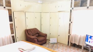 A bedroom with a bed, a brown armchair, a laptop on a small table, and a television on a stand. - 🌟🧡FREE AIRPORT/BUS TERMINAL TRANSPORTATION (Kumasi)