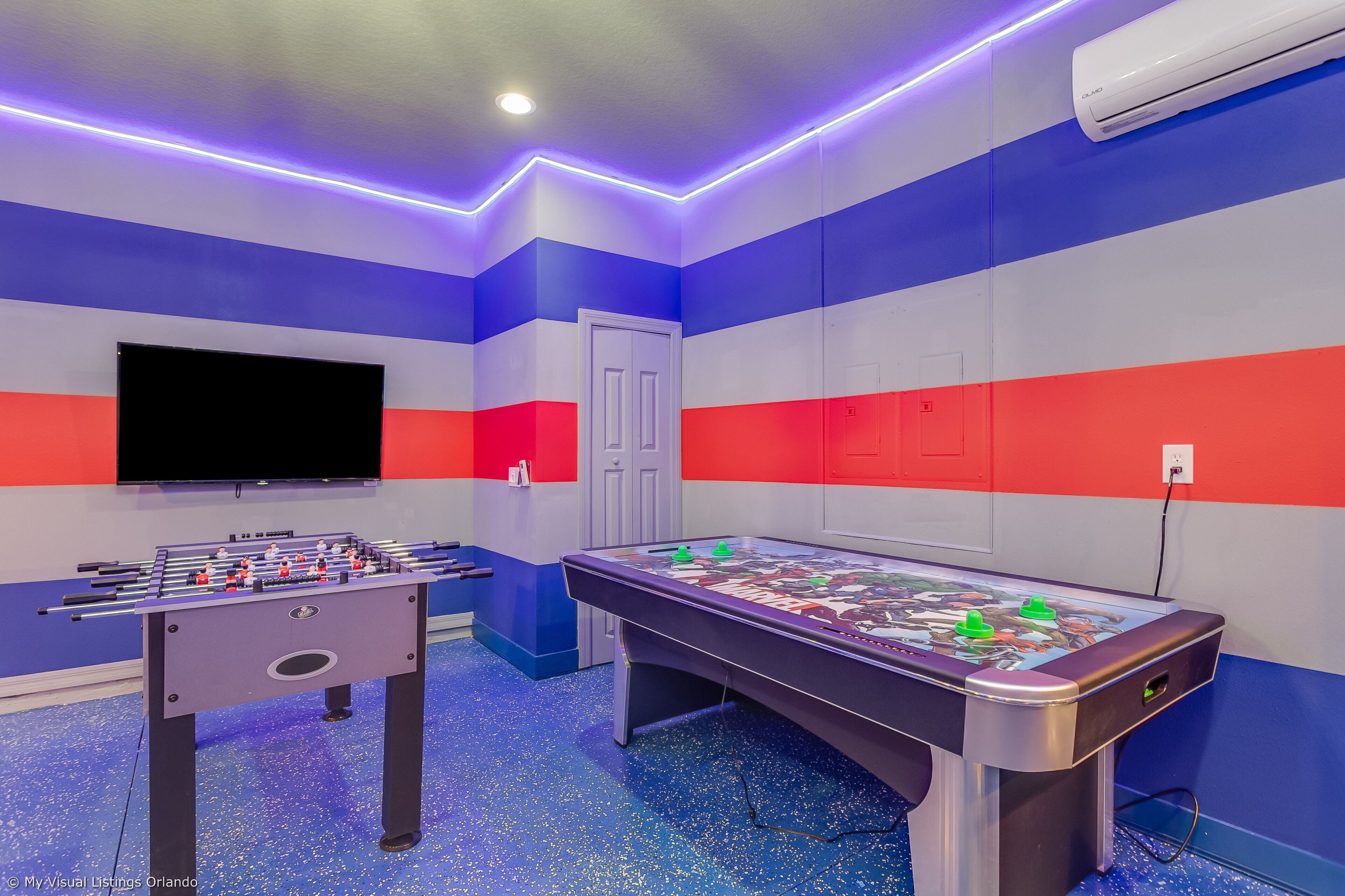 A room with a foosball table, a pool table, and a flat-screen TV.