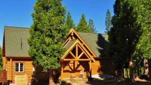 A log cabin with a prominent triangular roof and a stone foundation.