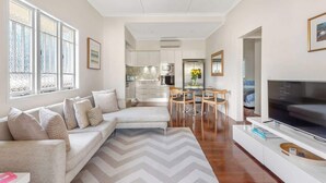 A modern living room with a sofa, TV, and dining area. - Modern Twist + Old World Charm ~ 3Bed/2Bath/2Car (Kedron)