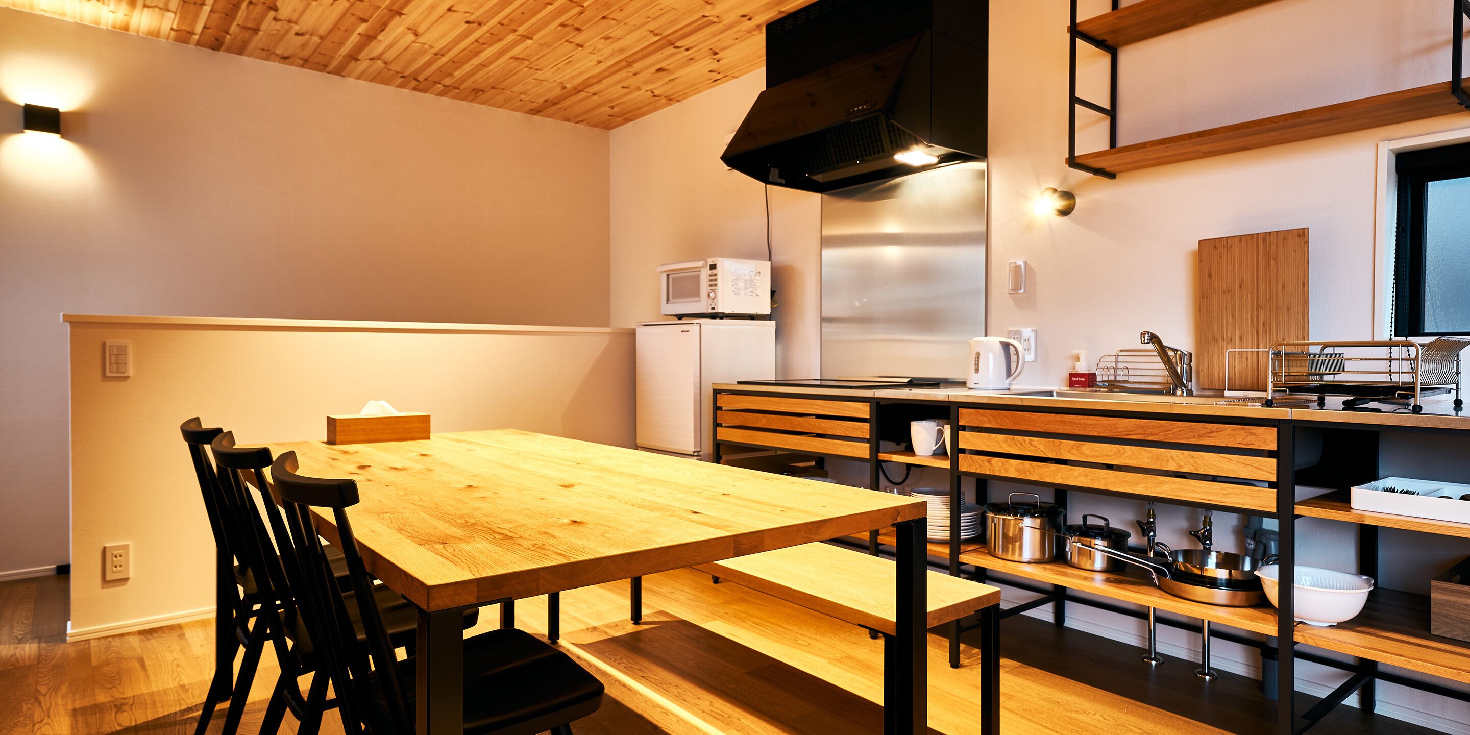 Una cocina moderna con armarios de madera, un refrigerador de acero inoxidable, un microondas y una cafetera.