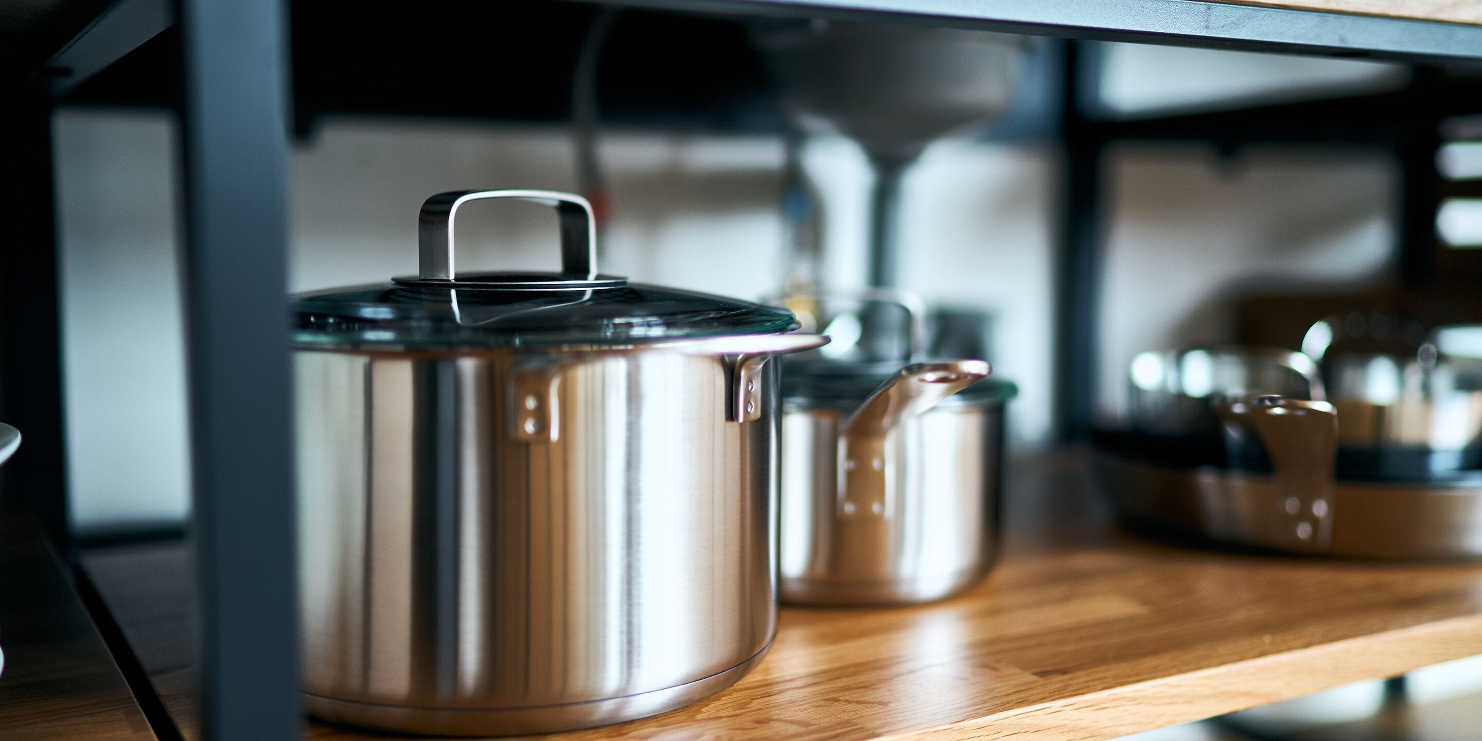 A stainless steel pot with a lid on a wooden surface.