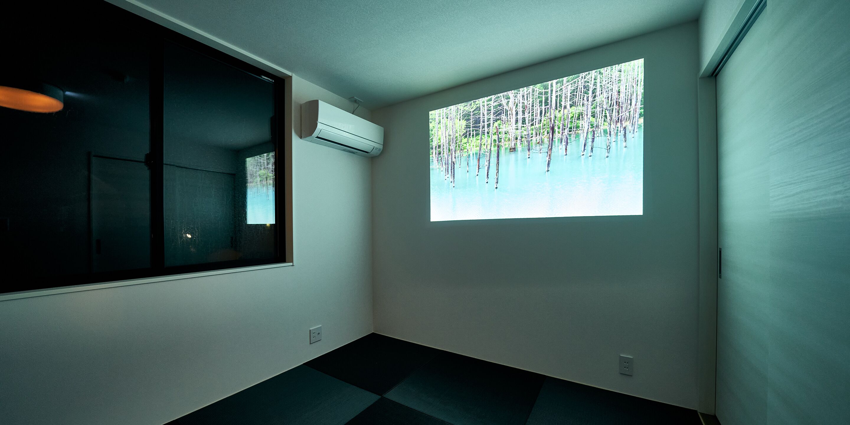 A room with a large window, air conditioning unit, and a view of trees.