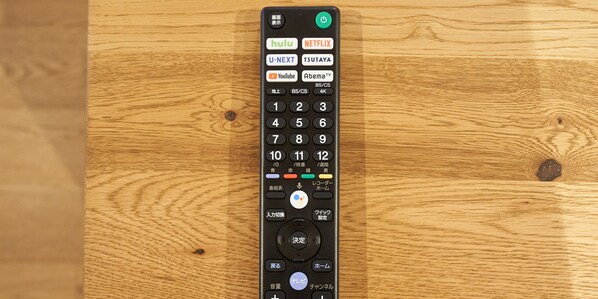 A remote control with various buttons and labels, including brand names and channel numbers.
