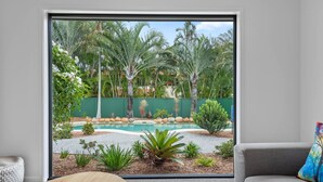 Una sala de estar moderna con un amplio ventanal corredizo que da a una zona de piscina.
