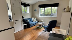A compact living space with a kitchenette, a sofa, a dining table, and a chair. - Hidden Gem - Bed & Breakfast (Upper Hutt)