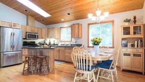 A modern kitchen with wooden cabinets, stainless steel appliances, and a central island with stools. - Summer Basecamp: Near Mt Baker, BBQ, AC, Fireplace (Glacier)