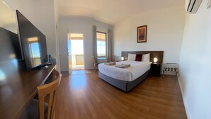 Habitación de hotel con cama, escritorio, silla, televisor y ventana.