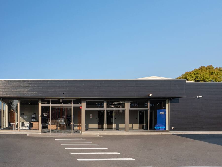 A modern building with a flat roof, large glass windows, and a clear sky.