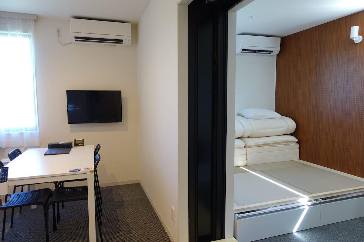 A hotel room with a bed, a desk, and a TV.