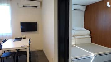 A hotel room with a bed, a desk, and a TV.