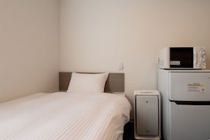 Una habitación de hotel con cama, microondas y refrigerador.
