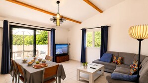 A living room with a TV, sofa, dining table, and a ceiling fan.