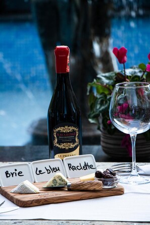 A bottle of Amarone wine, a glass of white wine, and a wooden board with cheese and olives. - Hotel Elysee (Tirana)