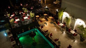 Un espace extérieur aménagé en terrasse, avec des tables et des chaises, une petite fontaine et des plantes en pot.