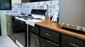 Eine Küche mit Herd, Backofen und einer gefliesten Spritzschutzwand.