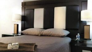 Ein Hotelzimmer mit einem großen Bett, zwei Nachttischen und einem Kopfteil mit vertikalen Paneelen.