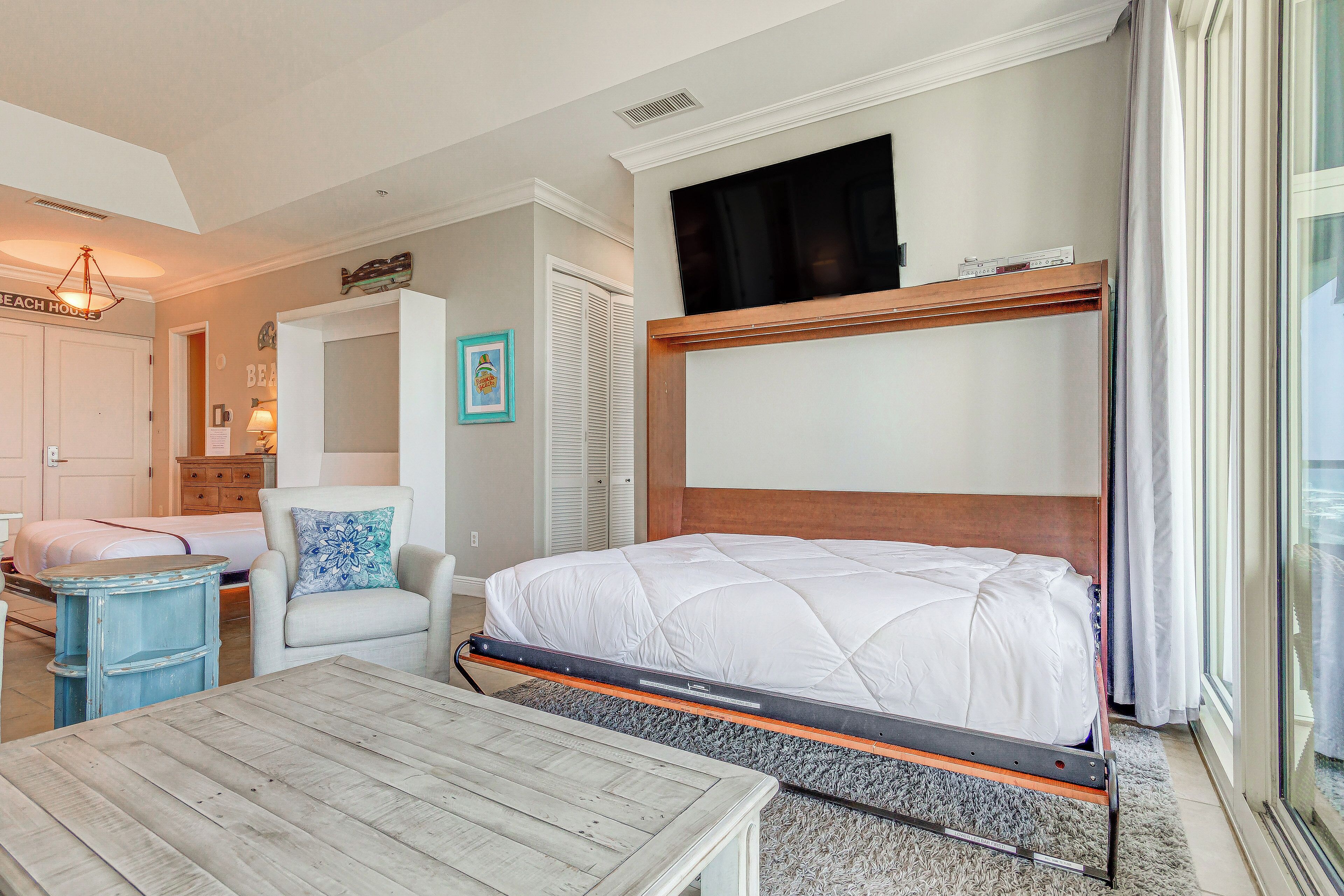 A bedroom with a bunk bed, a chair with a decorative pillow, a small table, and a dresser.