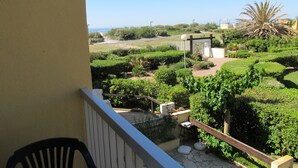 A balcony with a view of a landscaped garden, a palm tree, and a distant bridge.