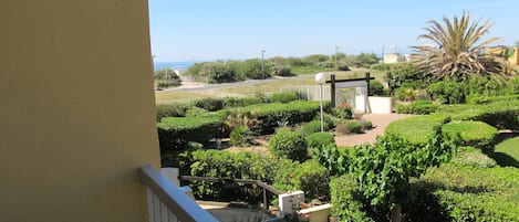 Un balcón con vistas a un jardín ajardinado, una palmera y un puente distante.