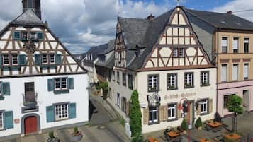 A traditional European street with half-timbered buildings, a clock tower, and outdoor seating areas.