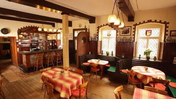 A cozy restaurant with wooden furniture, a bar area, and large windows with decorative glass panes.