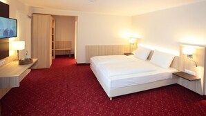 A hotel room with a large bed, two bedside tables, a TV, and a red carpeted floor. - Hotel zur Schloß-Schenke (Neuwied)