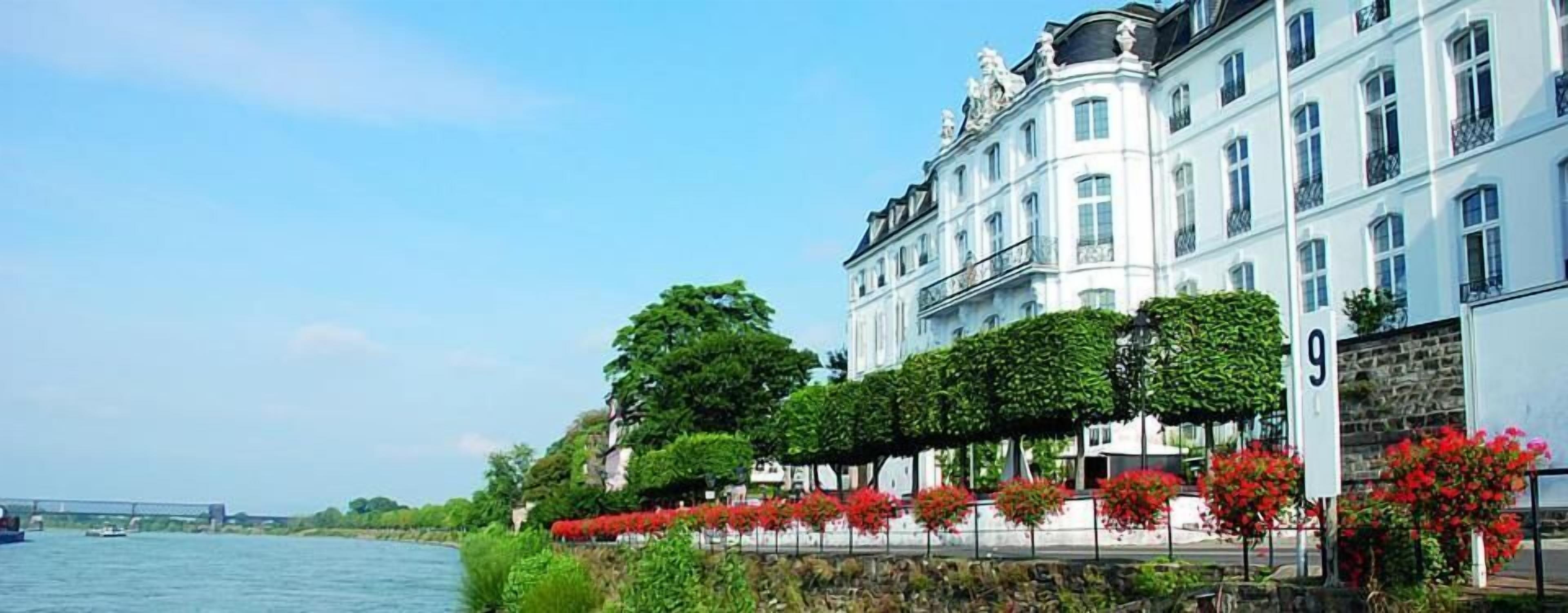A large, white building with classical architecture, located beside a river.