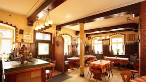 A cozy restaurant with wooden floors, brick walls, and a central bar area. Tables are set for dining, and there are decorative items on the walls. - Hotel zur Schloß-Schenke (Neuwied)