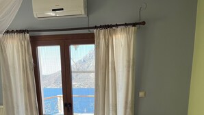 A hotel room with two single beds, a large sliding glass door leading to an outdoor area, and an air conditioning unit on the ceiling.