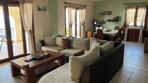 A living room with a sofa, coffee table, and dining area with chairs and a table.