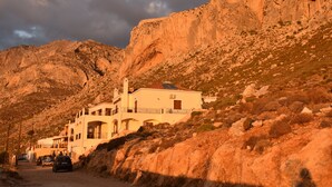 A building with a white facade, multiple balconies, and a mountainous backdrop.