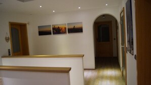 Ein Korridor mit einer Rezeption, drei gerahmten Bildern an der Wand und einer gewölbten Tür, die in einen anderen Raum führt.