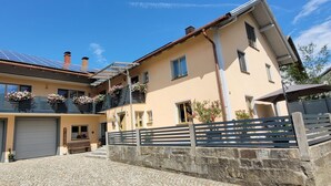 Ein zweigeschossiges Haus mit Garage, einem Balkon mit Blumenkästen und einer Steinmauer.
