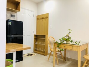 A compact room with a wooden desk, a chair, a television, and a wardrobe.