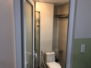 A small, compact bathroom with a glass-enclosed shower, a toilet, and a towel rack.