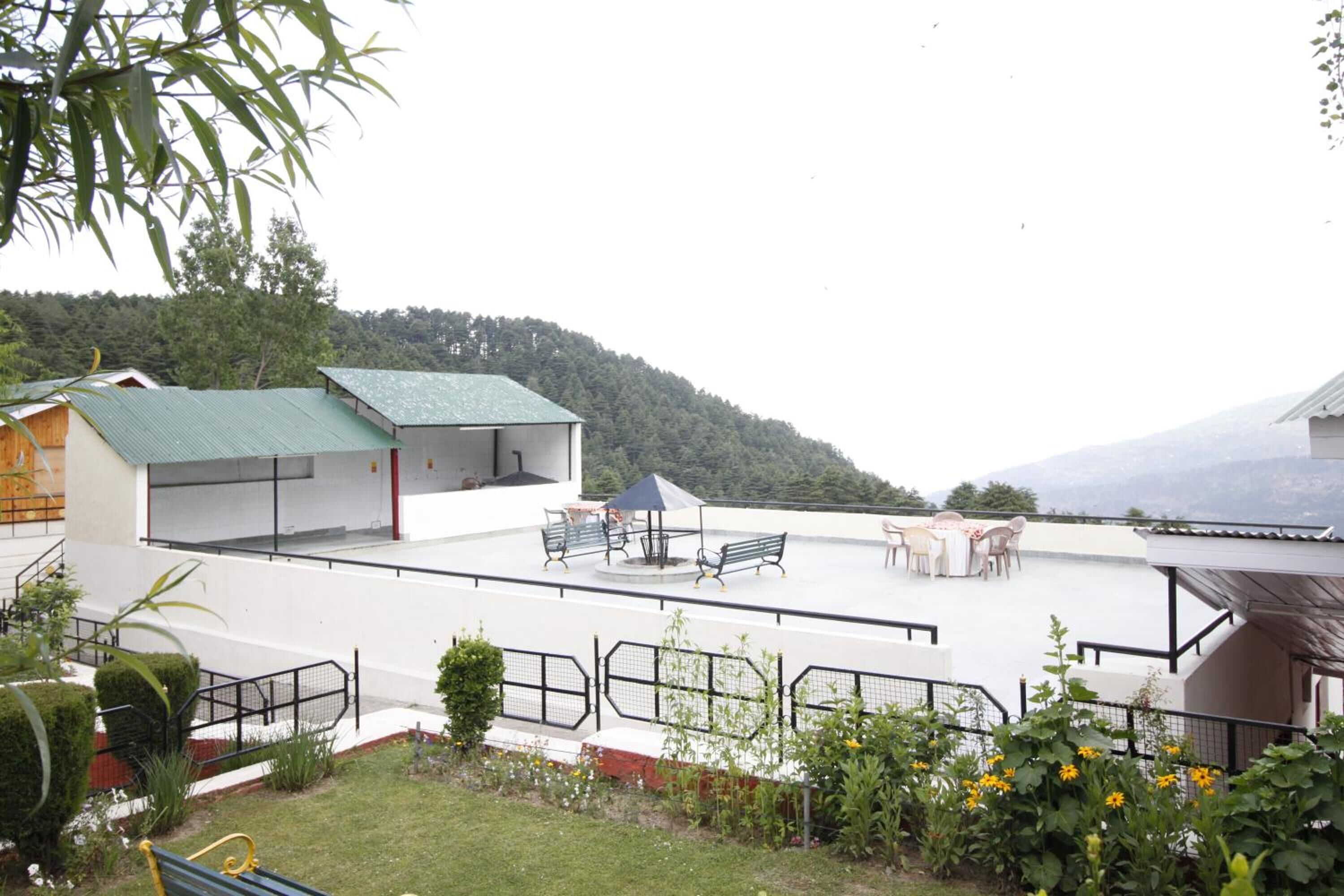 A rooftop terrace with outdoor seating, a covered area, and a view of a forested hill.